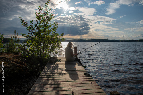 Woman sitting on the pier and fishing