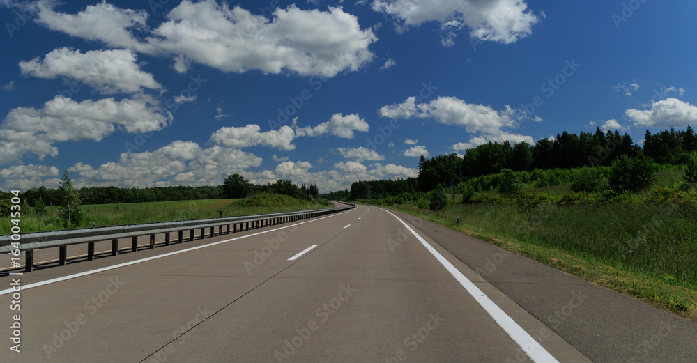 Fototapeta premium Road view on a summer day. Highways and cars, roadside and white road line markings.