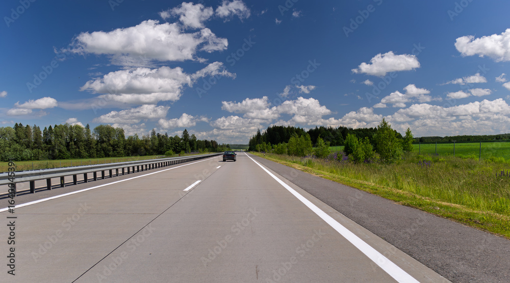 Naklejka premium Road view on a summer day. Highways and cars, roadside and white road line markings.
