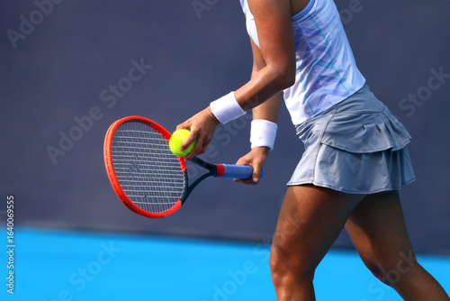 Female tennis player preparing serve with racket and ball on outdoor court