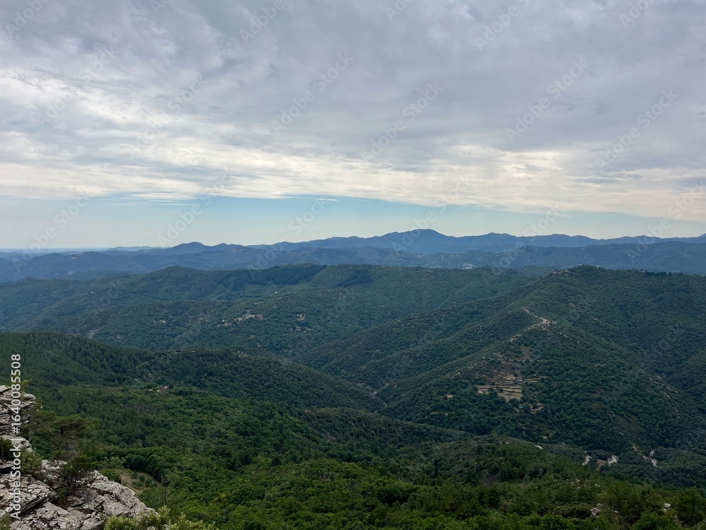 Fototapeta premium Stunning view soaring above the lush Cévennes forest under a vibrant sky painted with warm hues. Perfect for hiking (gr70, chemin de stevenson) and landscape photography.