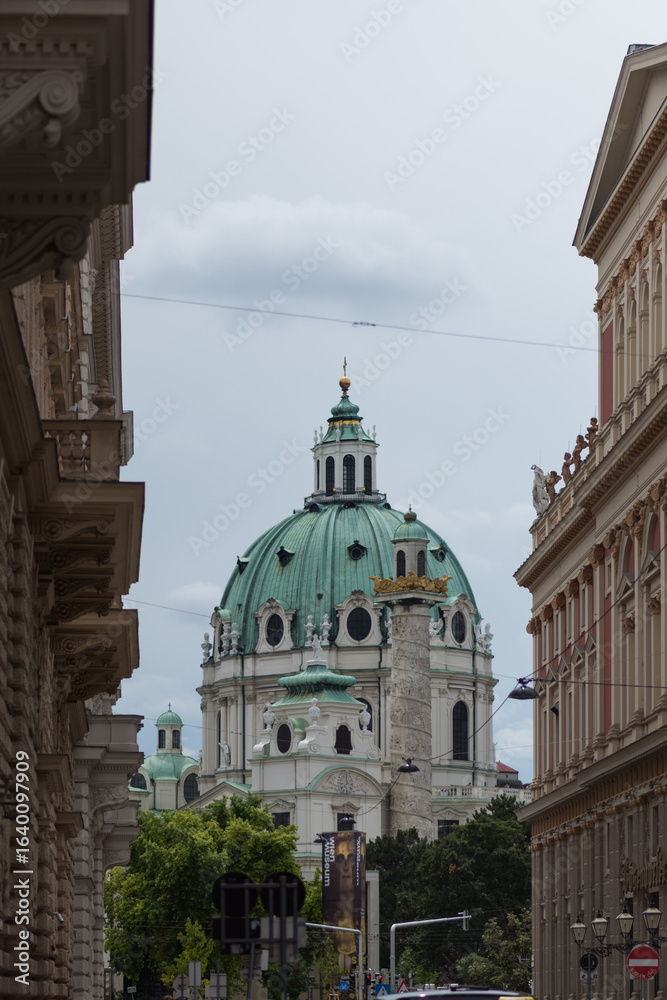 Fototapeta premium А prominent view of the Karlskirche (St. Charles's Church) in Vienna, framed by the facades of surrounding buildings. The church is a masterpiece of High Baroque architecture