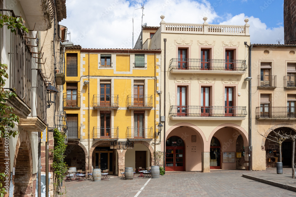 Obraz premium Main square of Prades, a charming village in Baix Camp, Tarragona, Catalonia, Spain, known as the “Red Town” for its distinctive reddish sandstone buildings.