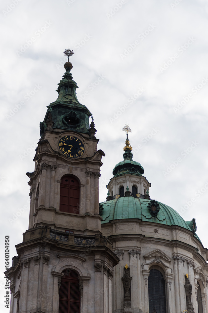 Fototapeta premium Church of St. Nicholas in Prague's Lesser Town. The image focuses on the main tower and the large, central dome of the Baroque-style church
