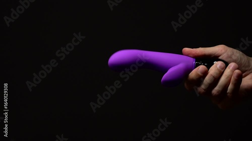 Purple rabbit vibrator for sexual pleasure and enjoyment.
Hand vibrator for orgasm on black isolated background.
Adult sex toys
