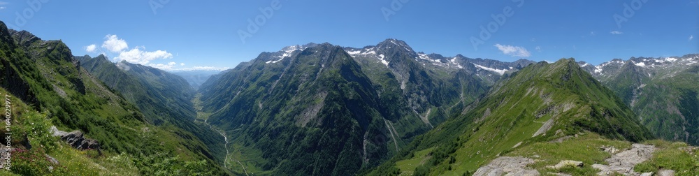 Panoramic mountain valley view. Lush green valley nestled between high, snow-capped peaks Panoramic mountain valley view. Lush green valley nestled between high, snow-capped peaks