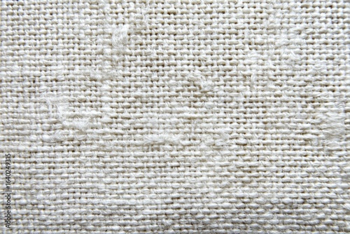 Close-up view of a textured white fabric.  The weave is clearly visible, creating a grid pattern.  Slight variations in the weave's density are apparent
