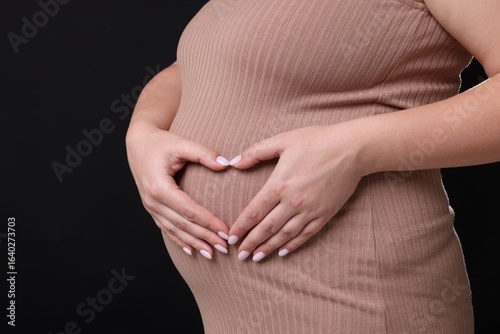 Wallpaper Mural Pregnant woman making heart with her hands on black background, closeup Torontodigital.ca