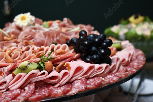 salami and vegetables, gourmet charcuterie board with cold cuts and fruits, assorted deli meats platter with grapes, luxury antipasto tray with flowers and nuts