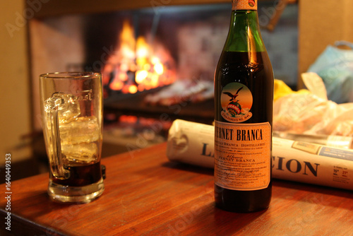Bottle of Fernet Branca with Glass and Asado in Background