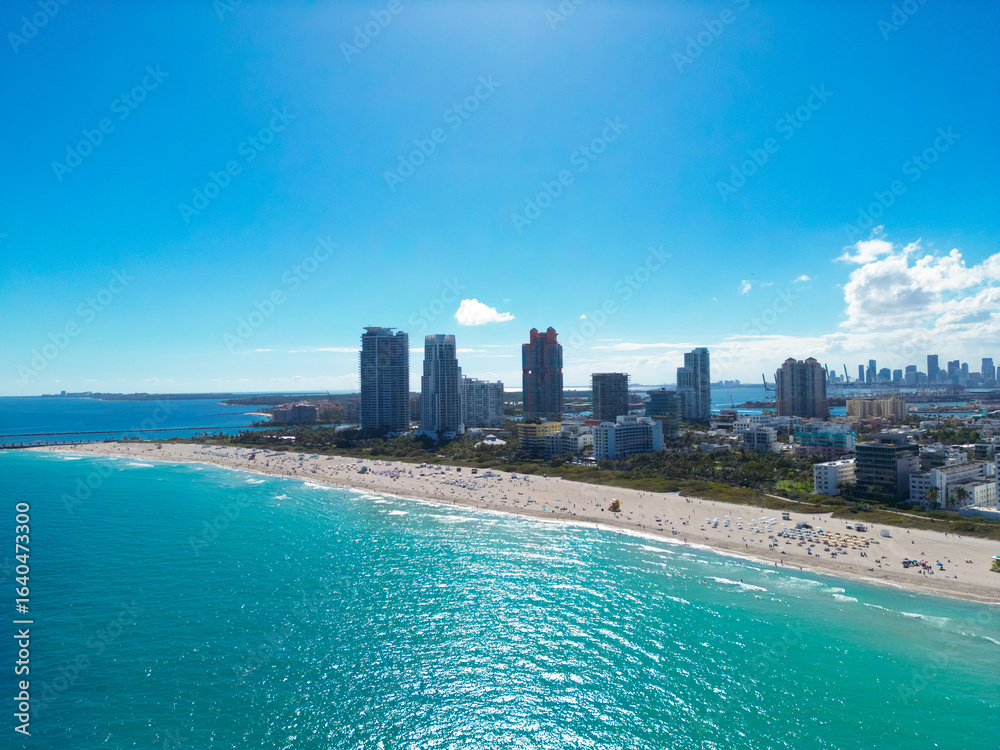 Naklejka premium Miami city landscape on blue sky with clouds. South beach coastal in Miami. Skyscrapers Miami, aerial view. South beach. Miami Beach pier. Miamis shoreline.
