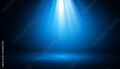 Bright blue spotlight shining on a dark, empty stage. Mysterious background with dramatic light rays for a show or presentation.