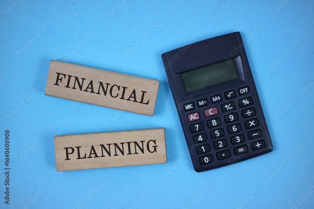 financial concept. wooden block with 'FINANCIAL PLANNING' written on it and calculator. isolated on blue background. top view financial concept. wooden block with 'FINANCIAL PLANNING' written on it and calculator. isolated on blue background. top view