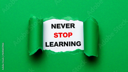 Naklejka Green paper torn revealing text never stop learning message