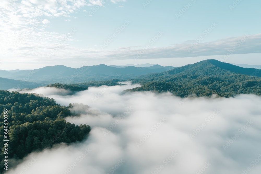 Obraz premium Panoramic Mountain Vista: A breathtaking panoramic shot, where verdant mountain range peaks emerge gracefully through a sea of ethereal clouds, with a bright blue sky above.