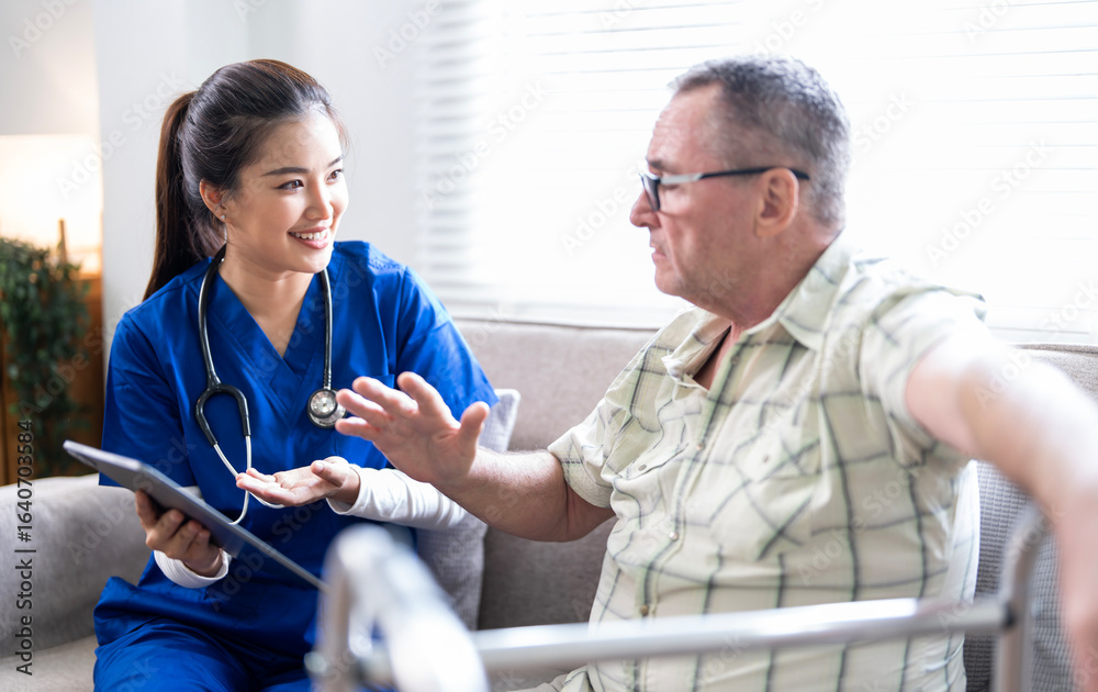 Fototapeta premium Smiling nurse in blue scrubs talking with elderly man using a walker, providing healthcare advice and support at home.