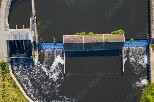 Top-down aerial view of Woolston Weir on the River Mersey in Warrington, a hydroelectric facility harnessing the river’s flow, with water cascading over the structure