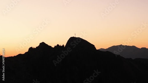 Drone video flying slowly upwards over the Italian Alps, capturing sunrise, mountain peaks, soft morning light, and peaceful alpine views.
