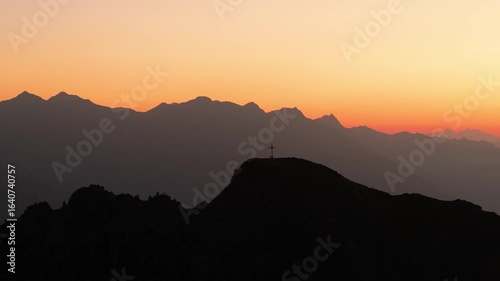 Drone video flying backwards slowly over the Italian Alps, capturing the sunrise, mountain peaks, soft morning light, and peaceful alpine scenery.