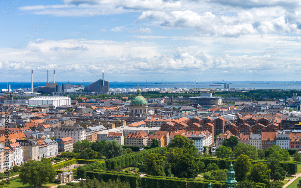 Obraz premium Aerial view of Copenhagen, Denmark, highlighting Frederik's Church, historic red tiled buildings, Amager Bakke, green gardens, and the Oresund Strait.