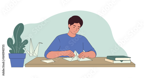 Man creating origami, with crane & books by table plant, soft colors