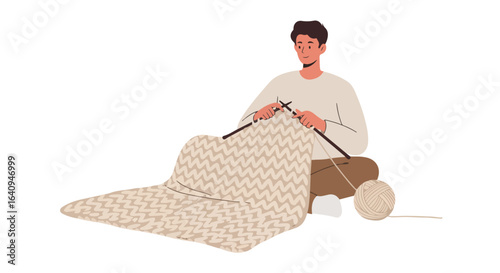 Knitter Man seated, knitting with needles, a large finished blanket beside him