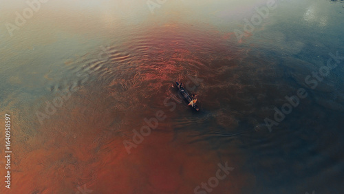 Silhouette of Traditional Fishing Boat on Reflective Morning Water.