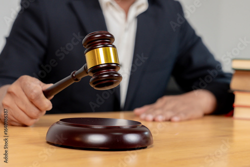 Close-up view of a judge's hand holding a wooden gavel in a courtroom.