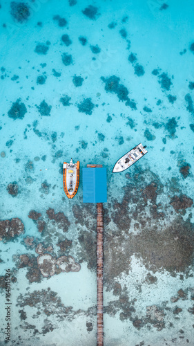 Aerial view of boats moored at a pier with a blue roof amidst the vibrant turquoise waters and coral reefs, Fakarava, Iles Tuamotu-Gambier, French Polynesia.