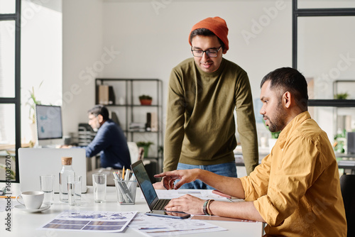 South Asian managers wearing smart casual clothes discussing survey results at work in office