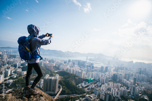 Canvas Print Successful woman hiker stand on the cliff edge taking selfie with smartphone in