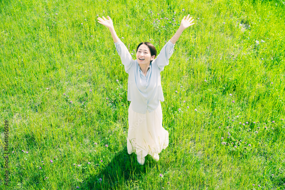 草原でストレッチをする若い女性 ライフスタイルイメージ 草原でストレッチをする若い女性 ライフスタイルイメージ