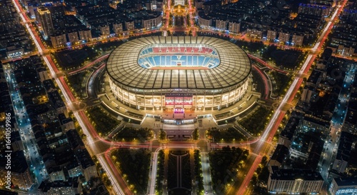 Illuminated stadium against a nighttime urban landscape with vibrant car trails