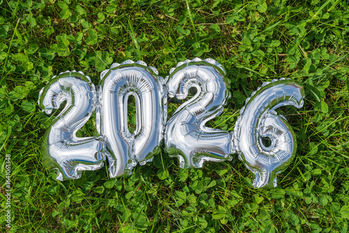 Silver balloons display 2026 on green grass background