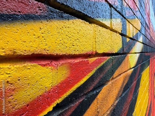 Colorful Brick Wall With Graffiti Featuring Yellow, Red, and Black Shades