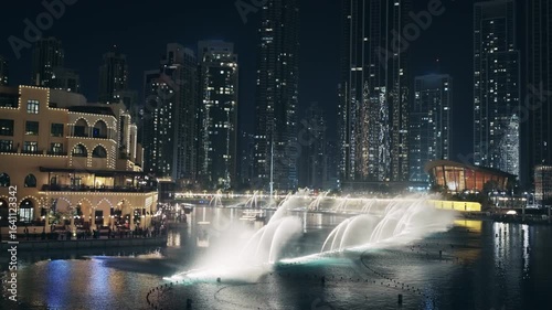 Aerial night view of water fountain show in Dubai Downtown near the Opera with illuminated skyscrapers at background