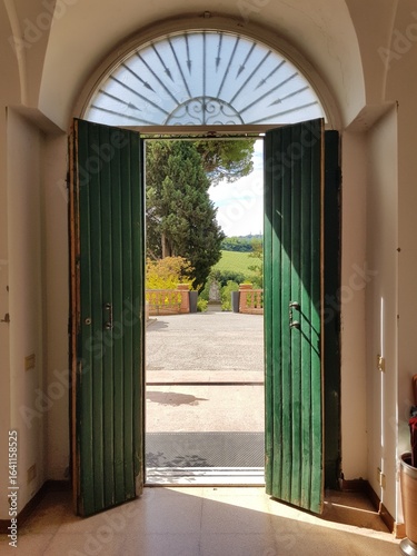 View through an antique wooden door onto fields in Tuscany