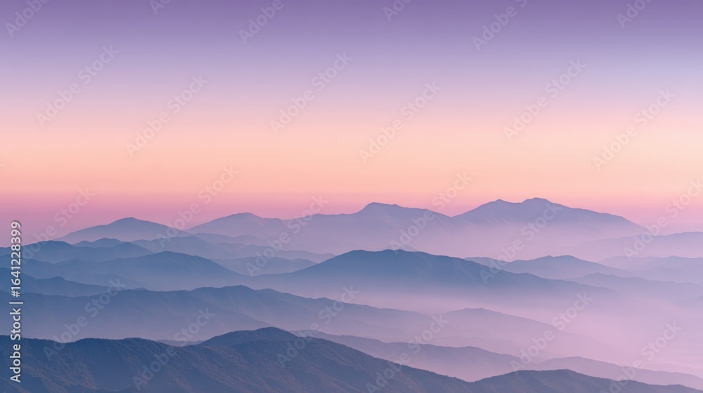 Obraz premium A breathtaking panoramic view of a majestic mountain range shrouded in a mystical layer of fog, bathed in the soft, warm glow of a sunrise or sunset, creating a serene and ethereal atmosphere.