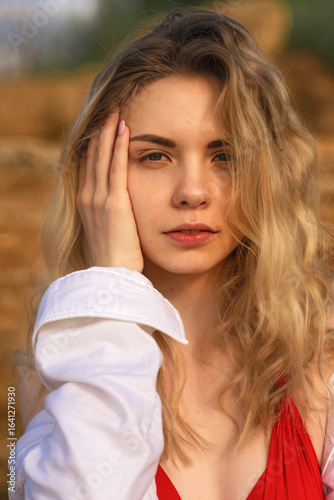 Close-up of cute blonde in red swimsuit and white shirt on the background of rock
