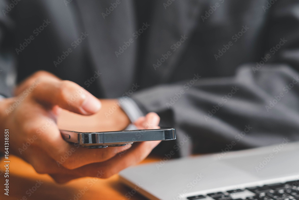 Businessman using laptop and smartphone in modern office, typing email, reading company policy online with coffee. Technology, HR, communication, internet browsing at workspace. Businessman using laptop and smartphone in modern office, typing email, reading company policy online with coffee. Technology, HR, communication, internet browsing at workspace.