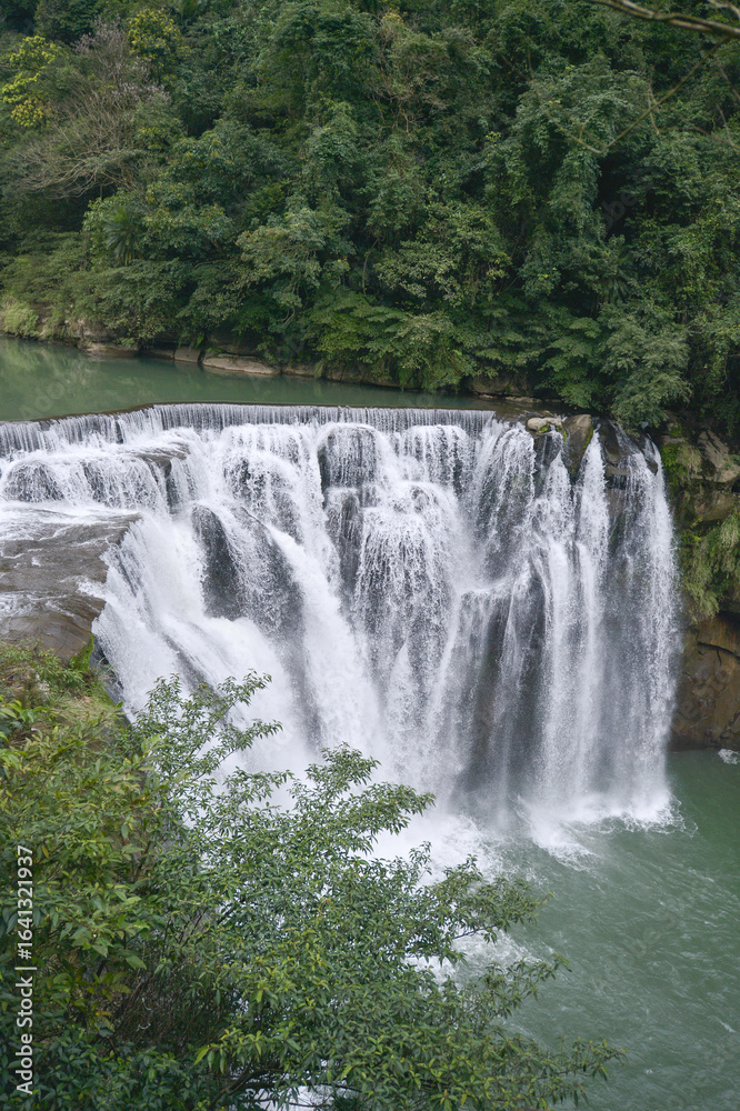 Fototapeta premium Majestic Cascading Waterfall in Lush Green Forest for Eco-Tourism and Nature Travel