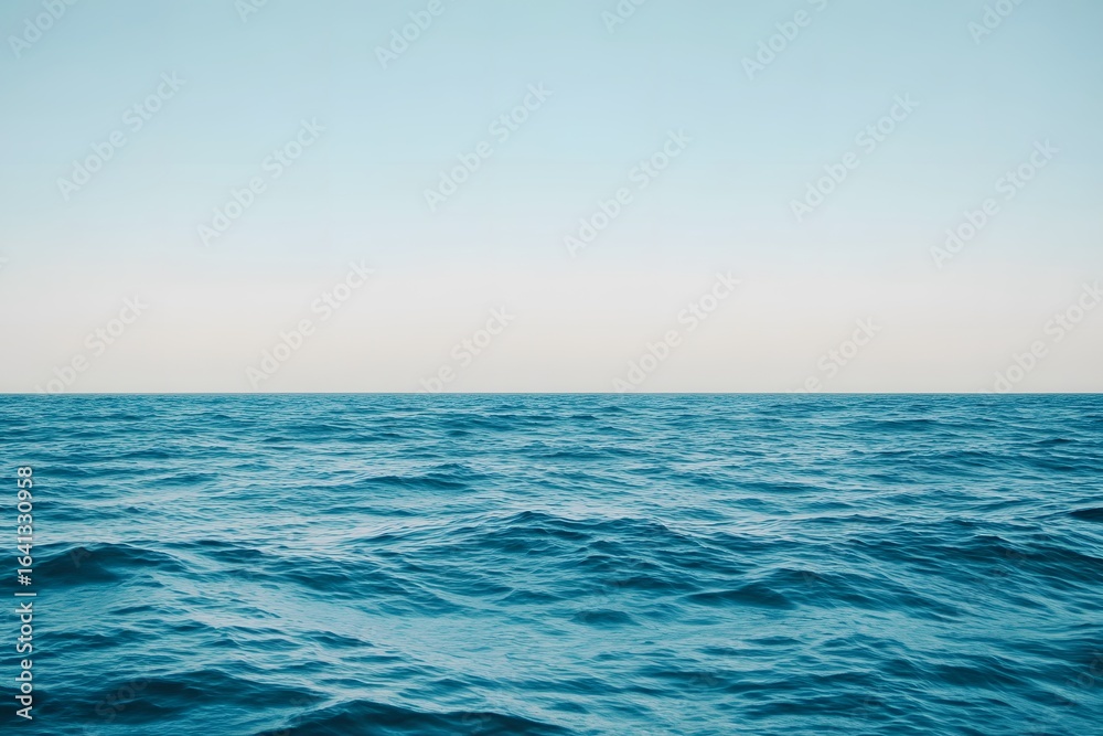 Obraz premium Calm blue ocean waves beneath clear sky, soft minimal light creating peaceful, relaxing background atmosphere.