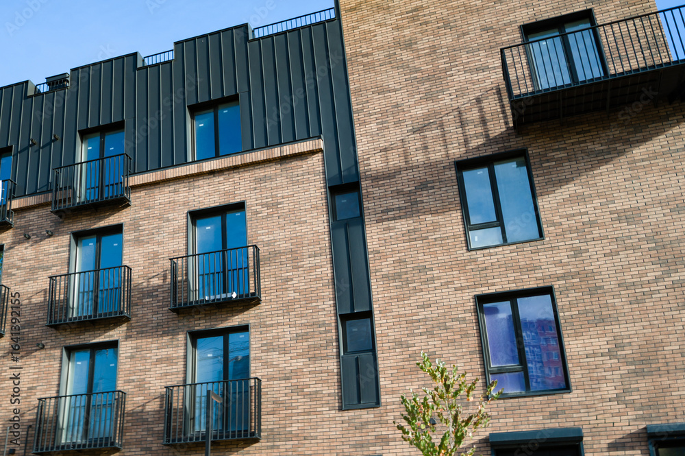 Obraz premium Modern architectural design showcases a blend of brick and metal elements in a stylish urban setting during a sunny afternoon