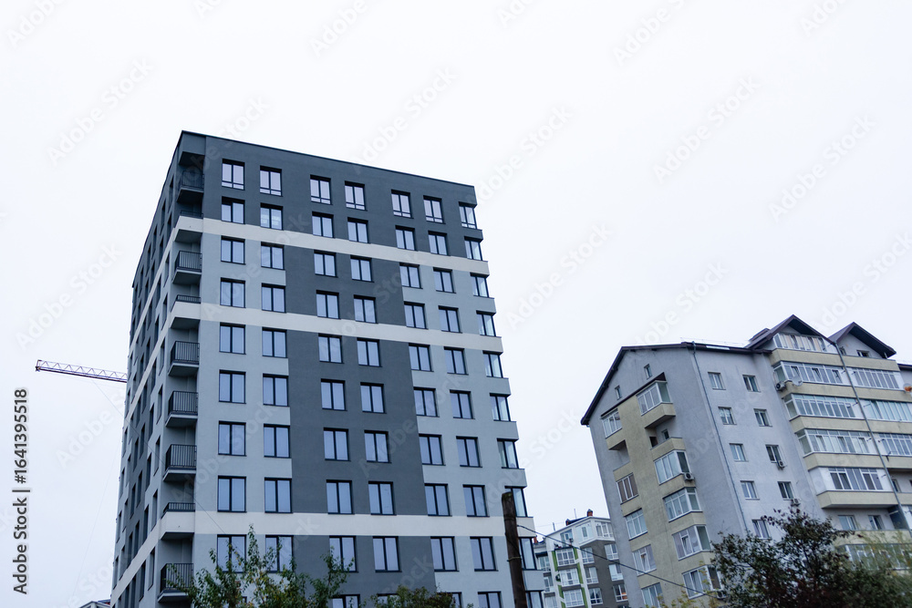 Fototapeta premium Modern apartment buildings rise against a gray sky in a contemporary urban setting