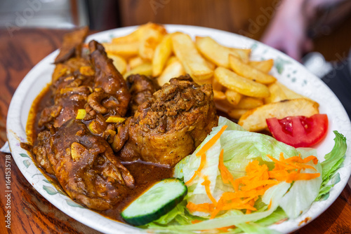 Traditional Maltese rabbit stew with fries and salad in Mdina, Malta.