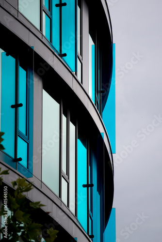 Obraz na plátně Curved modern building facade featuring large glass windows with striking blue tinted glass panels