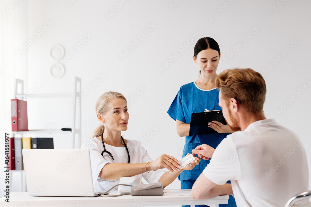 Obraz premium Doctor in white coat consulting with male patient, while nurse assists with medical supplies in modern clinic, showcasing healthcare teamwork and patient care environment