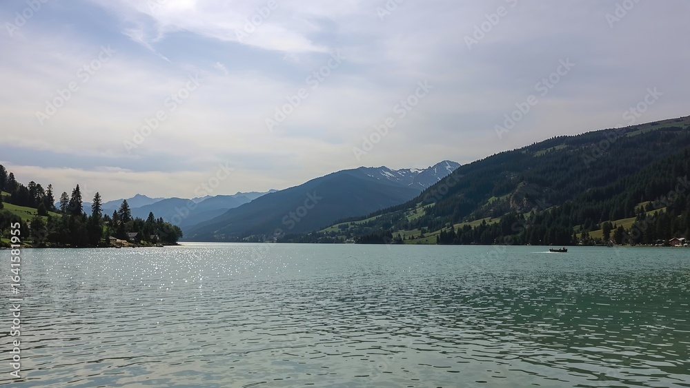 Fototapeta premium Panoramic scene featuring a lake bordered by undulating hills and cloudy weather