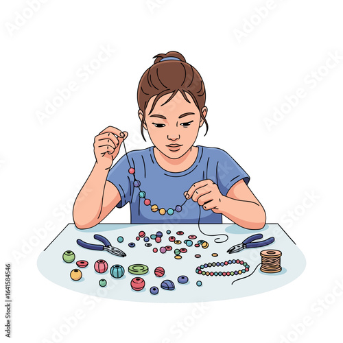 Young girl with a bun hairstyle carefully stringing colorful beads to create handmade jewelry.