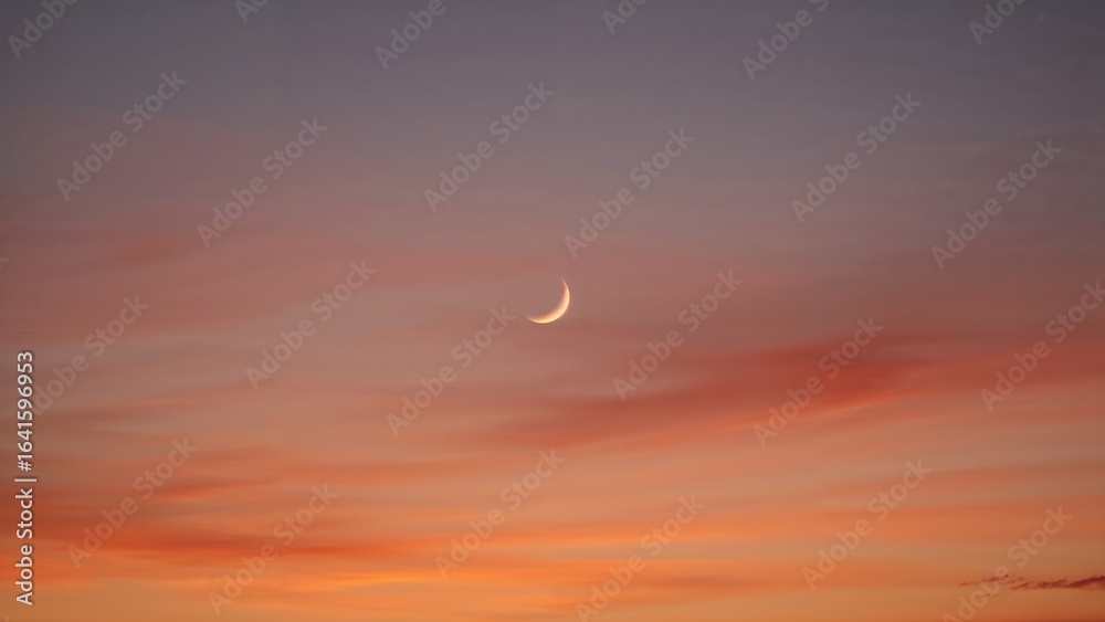 Fototapeta premium Summer and autumn sky background with a crescent moon illuminated by sunset colors
